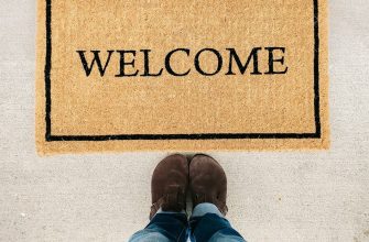 person in blue denim jeans standing on brown and black welcome area rug