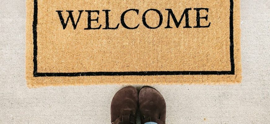 person in blue denim jeans standing on brown and black welcome area rug